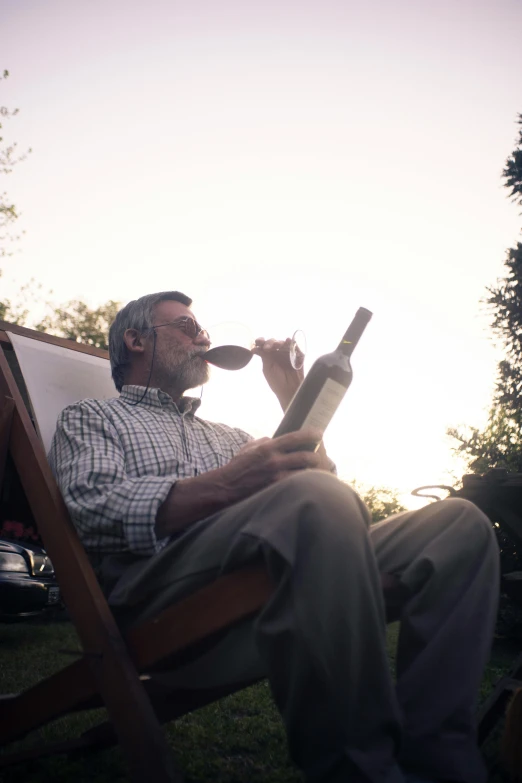 the man is drinking water while sitting in the chair