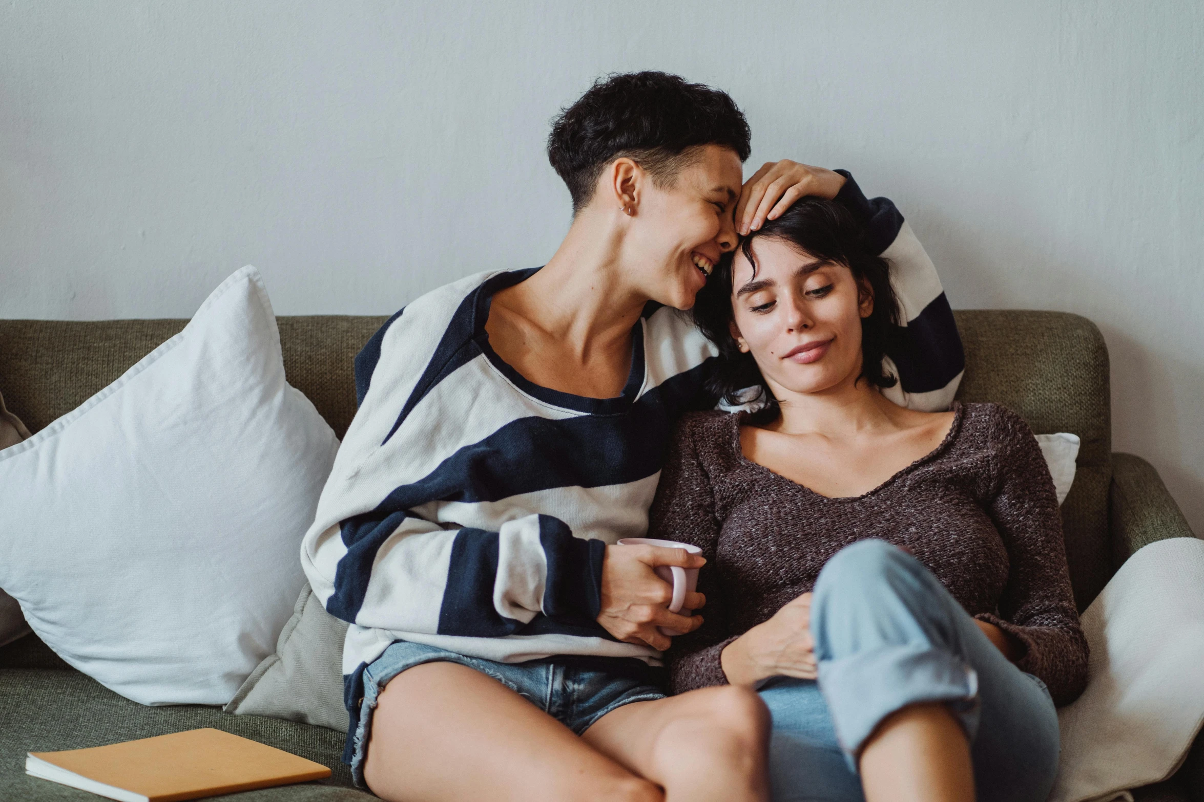 a couple cuddling and smiling while sitting on a couch