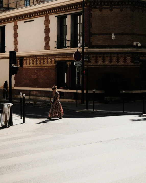 a woman is walking on the sidewalk in the sun