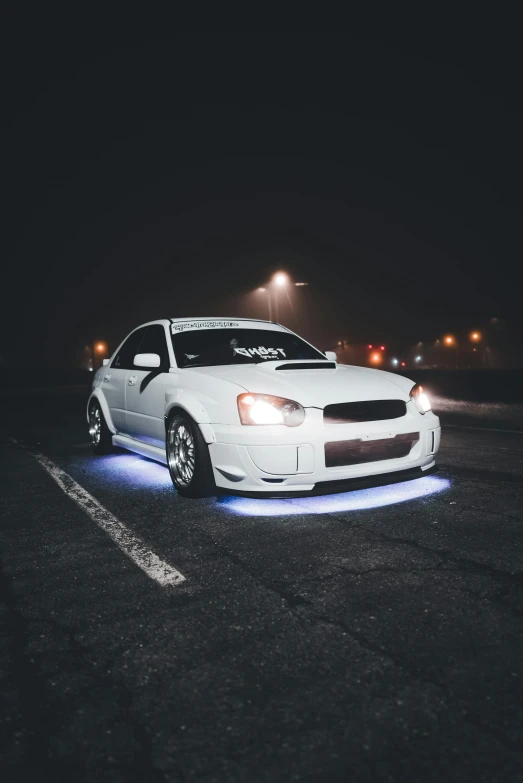 a car is sitting in a parking lot with its lights on