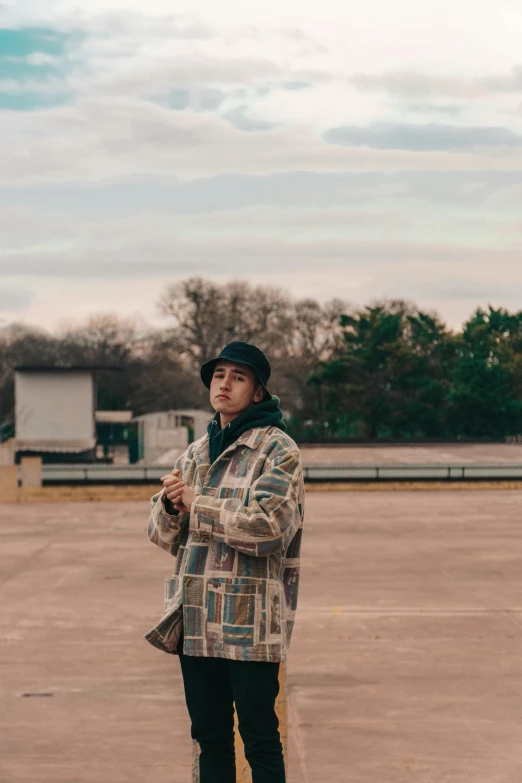 a man with a black hat and plaid coat standing on a skateboard in a parking lot