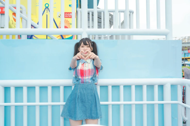 the woman is making a hand gesture while leaning on the fence