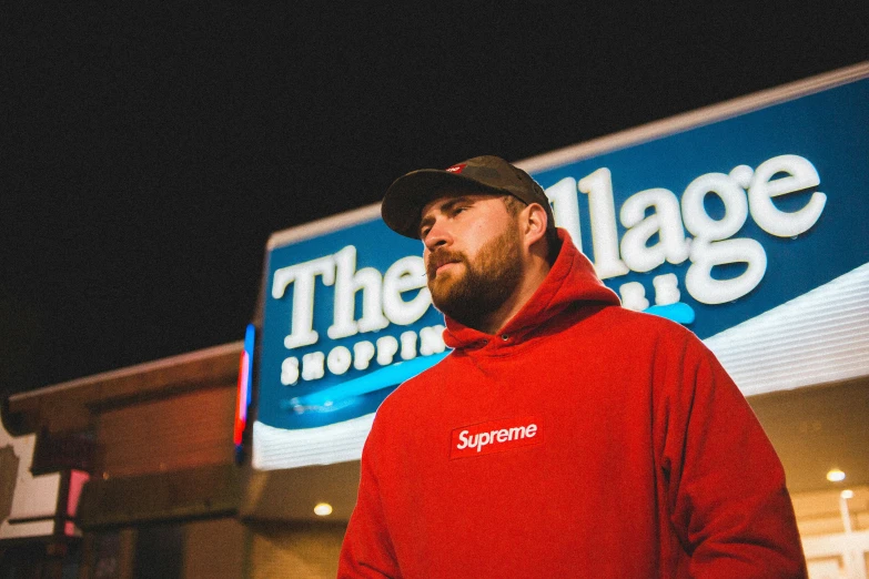 man in red sweatshirt outside the village shopping center at night