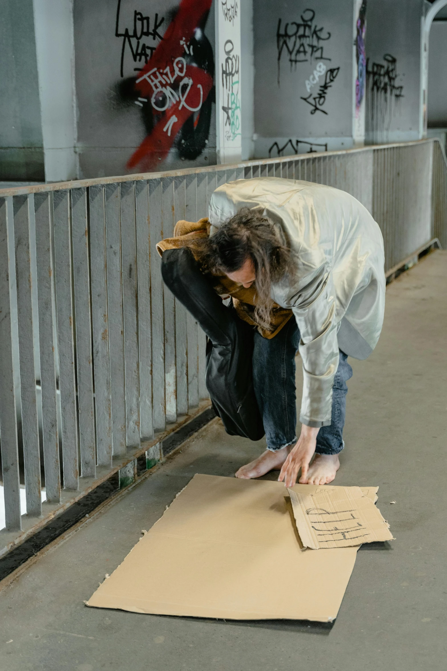 a woman bends over to help make a hand sign on cardboard