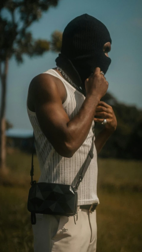 a man with a black mask covering his face holding onto his hand