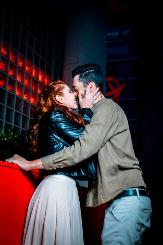 a couple is kissing against the wall with lights on