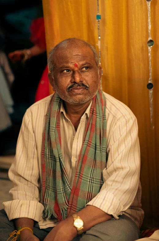 a man sitting on the ground with a colorful blanket