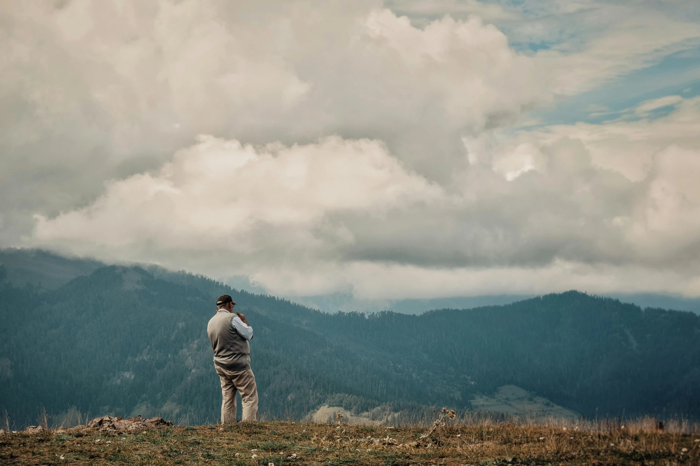 the man is looking at the mountain from the hilltop