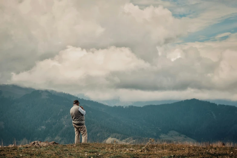 the man is looking at the mountain from the hilltop