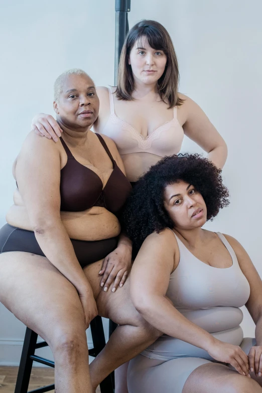 three women pose with one of them leaning on the other