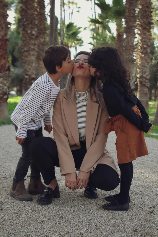 a man and two children are sitting on a park bench kissing