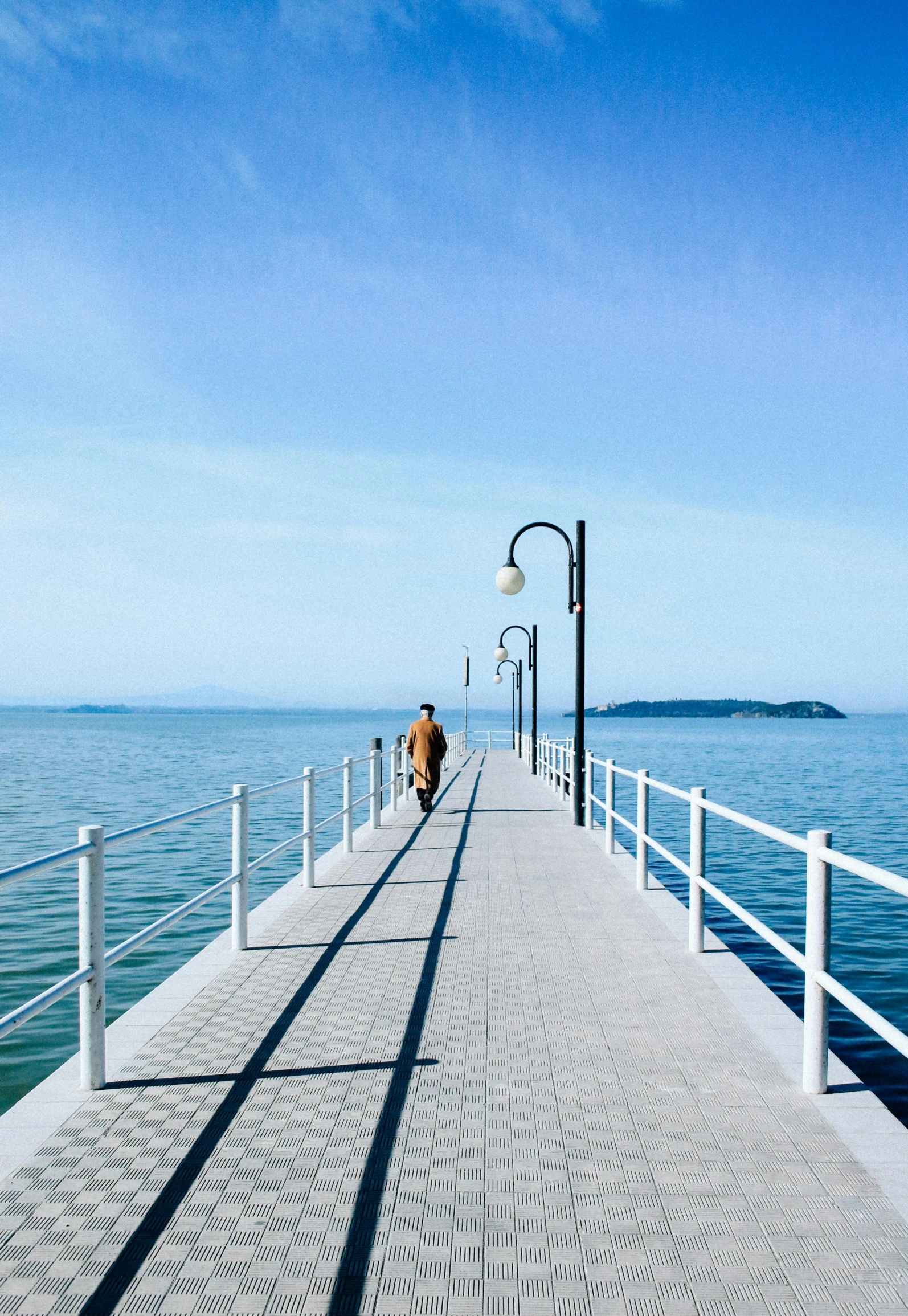 a pier at the beach with a man walking towards the water