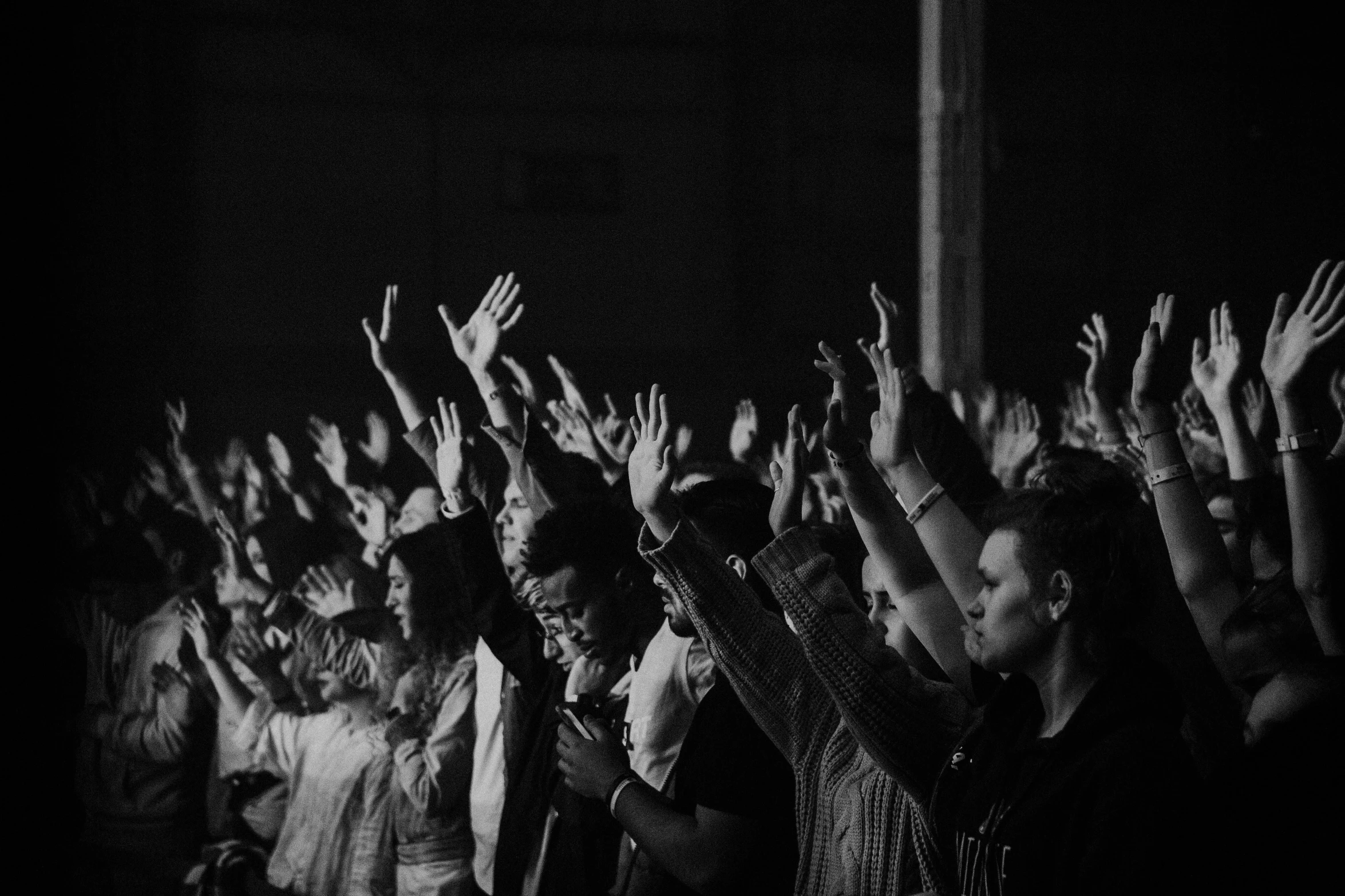 a crowd of people raising their hands up