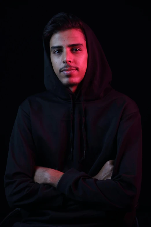 young man with hoodie looking at camera, in dark