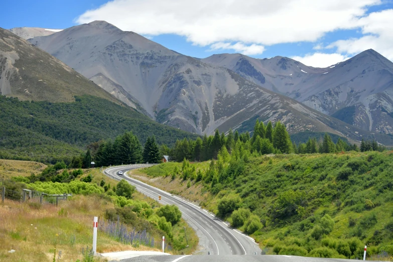 the road winds through the mountains with a speed limit sign on the right side