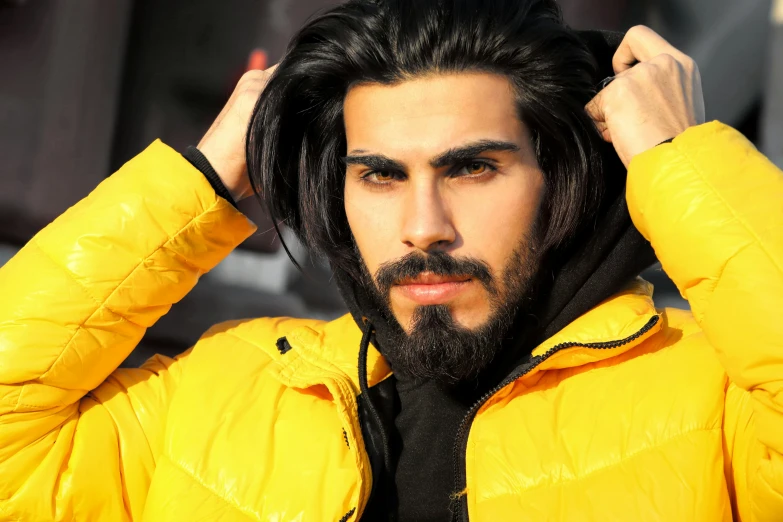 a man with black hair wearing yellow jacket