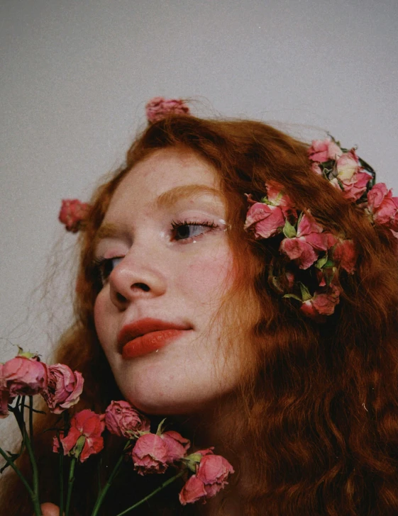 the girl has long hair and is holding pink flowers