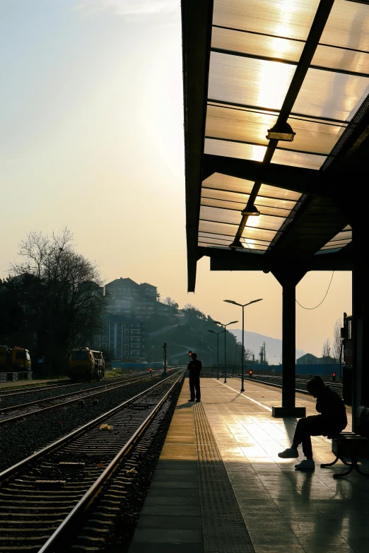 there is a man sitting on the side of the train station