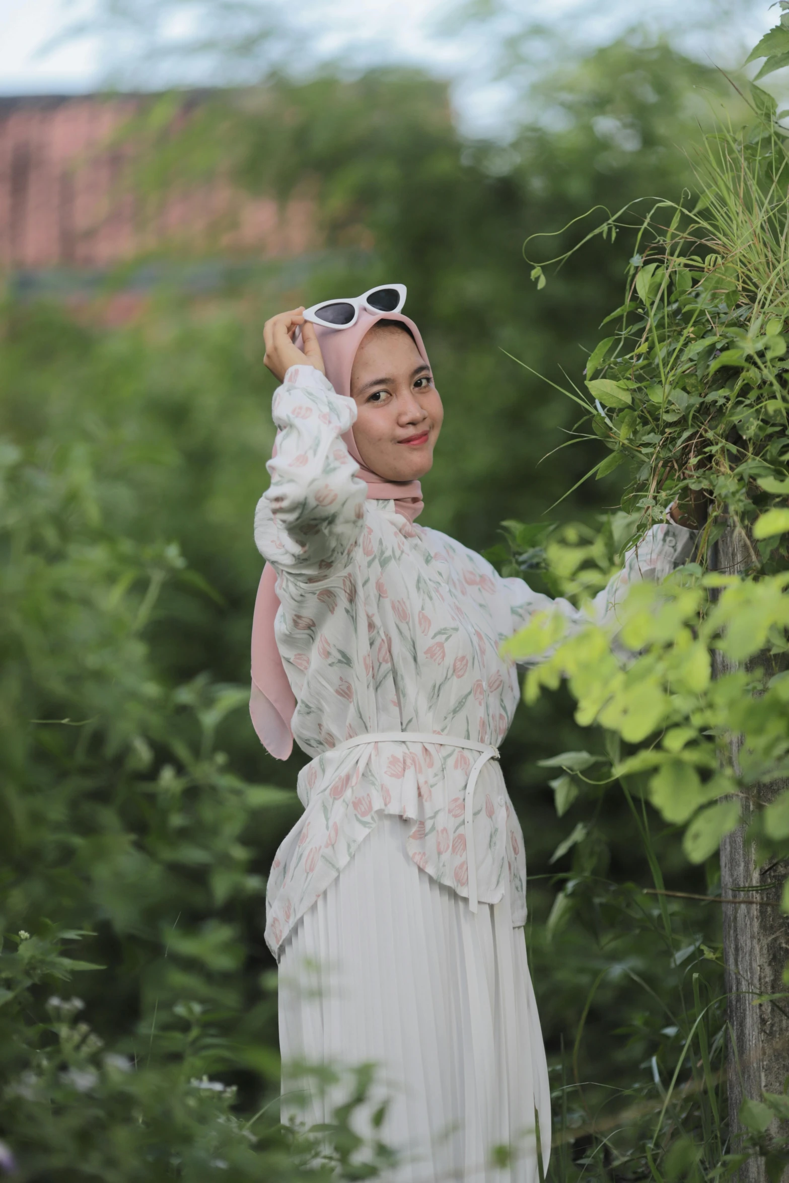 a beautiful woman standing next to a tree in a park