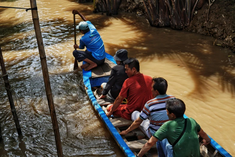 a man is rowing a long boat in muddy water