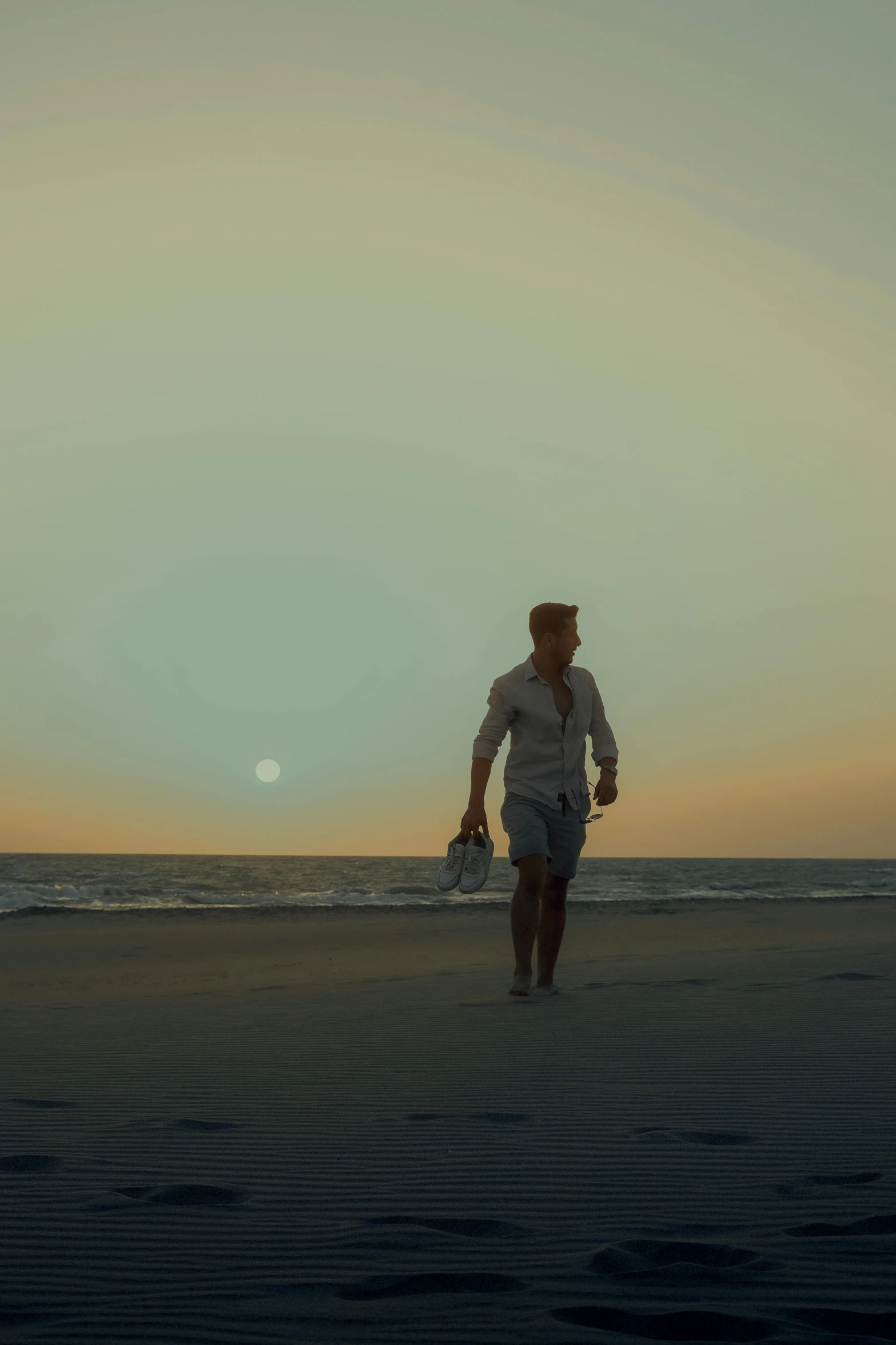 a man on the beach walking towards the ocean