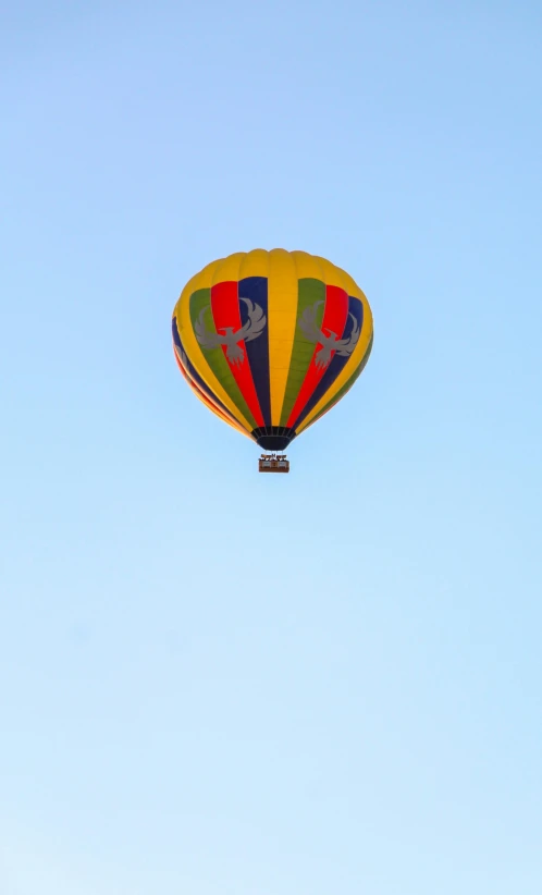 a yellow red and blue balloon flying high in the sky