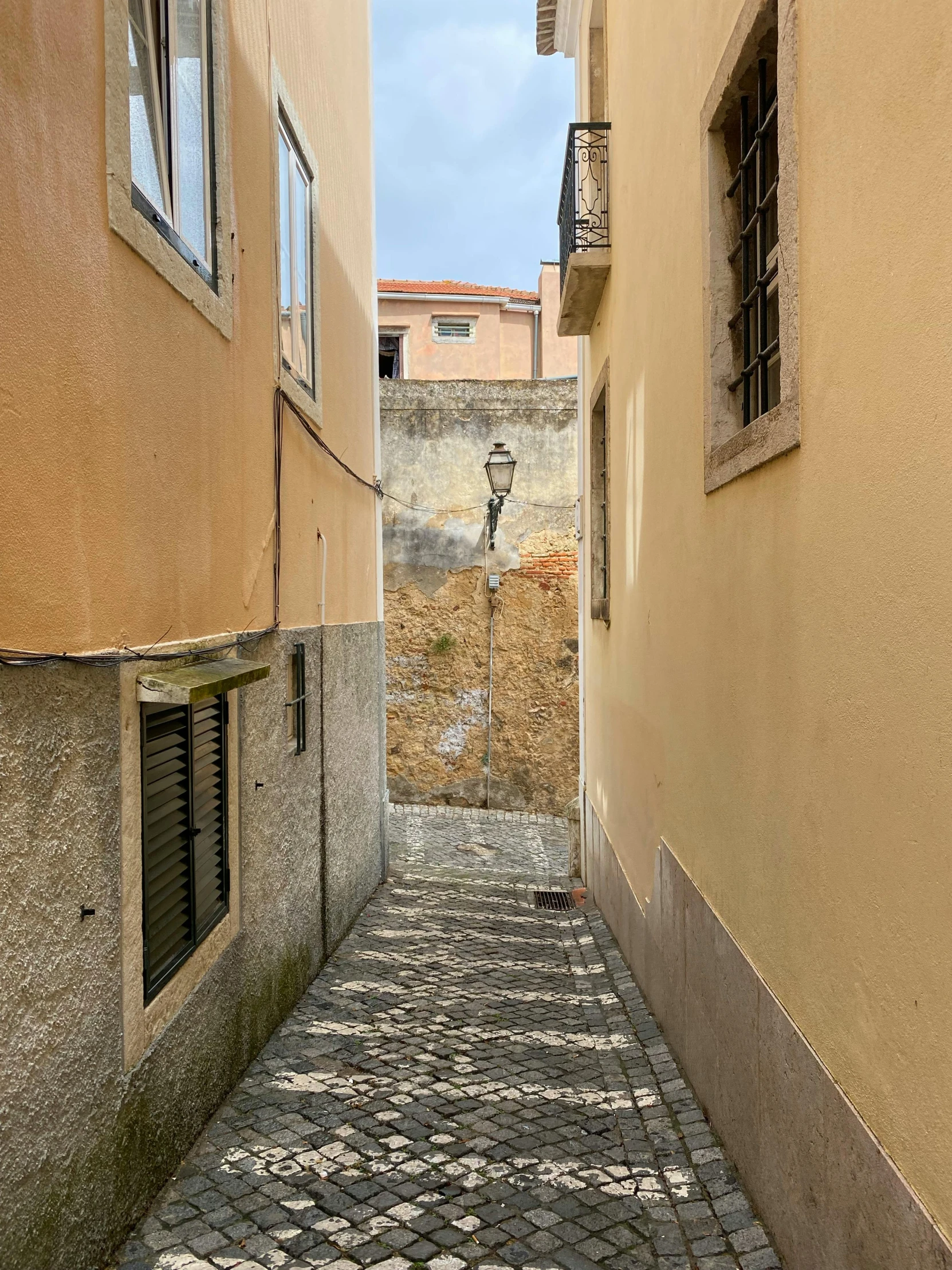 an empty stone street with two windows and some buildings