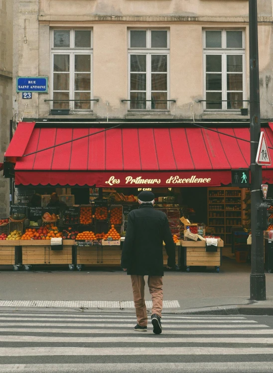 the shopper walks across the street and approaches a red awning