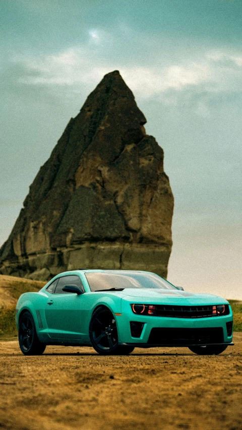 a very pretty looking car by a big rock