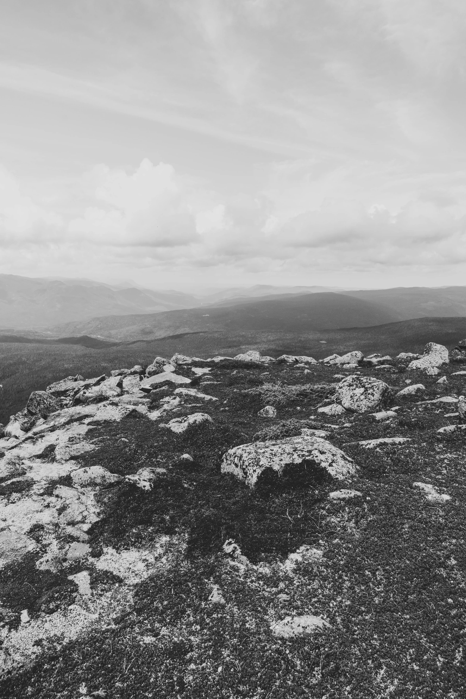 a man is standing on a ledge with mountains in the background