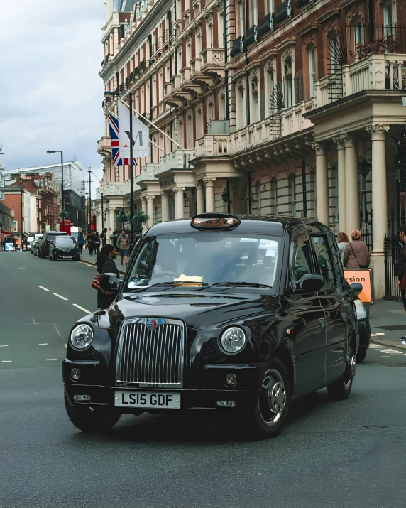 a taxi on the road with tall buildings in the background