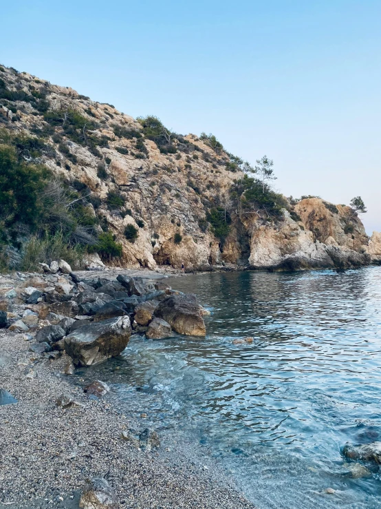 the rocky shore with an island and cliff in the distance