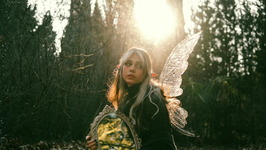 a woman in costume holding an object standing in the forest