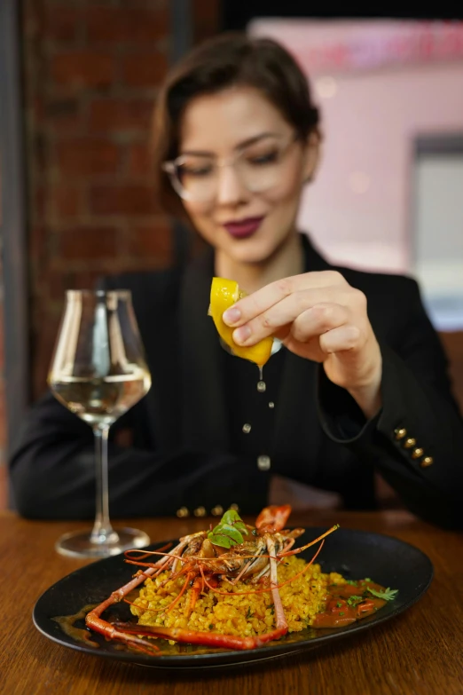 a woman sits at the table holding an orange piece of food