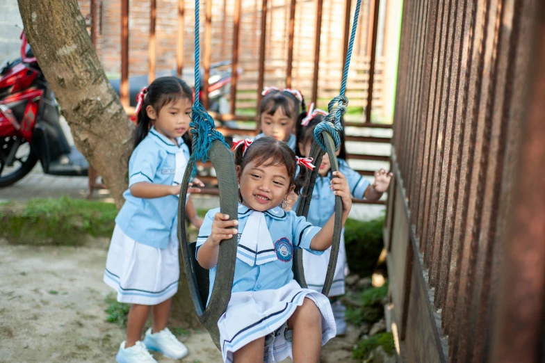 three girls hanging upside down on swings near the wall