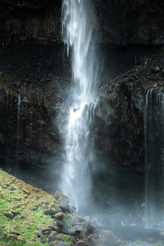 a waterfall is seen in the midst of a grassy area