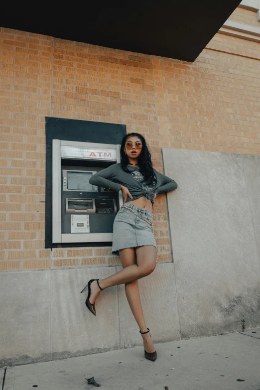 woman in gray sweater and grey skirt leaning on a wall