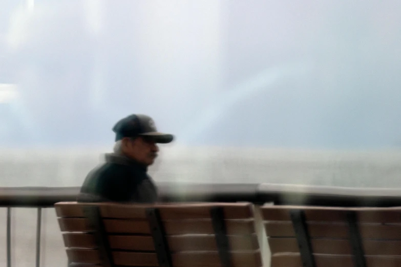 two people sitting on a bench near a fence