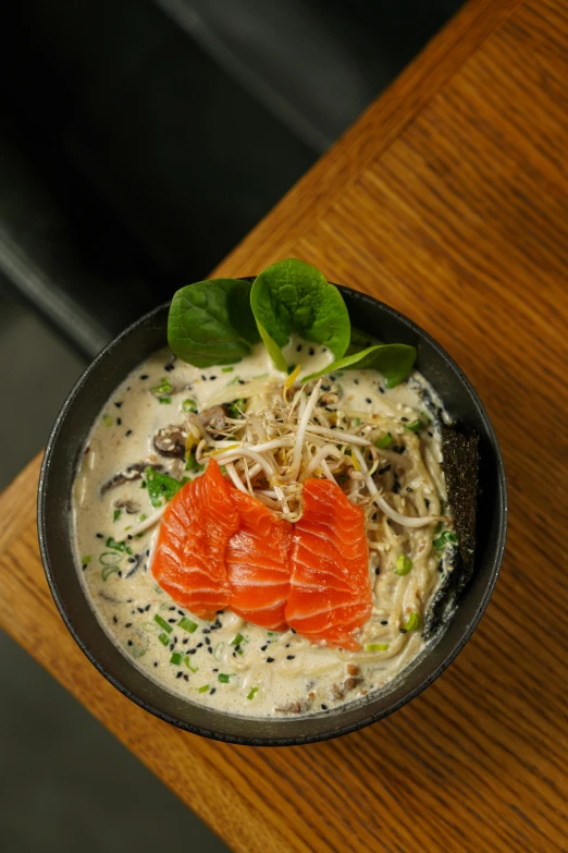 a bowl filled with cream and sauce and topped with two fresh salmon pieces