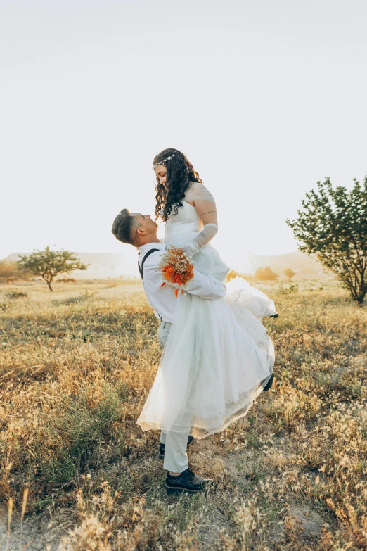 an adult is holding a  as they dance together in the field