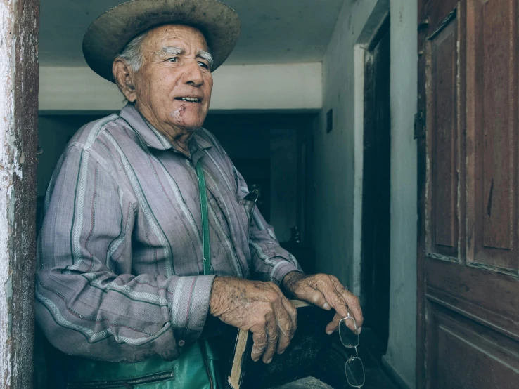 an older man dressed in blue and green with a cowboy hat on