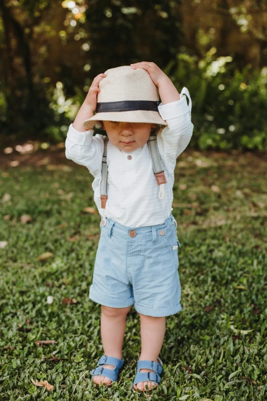 a little boy in blue jeans and a hat is looking at soing