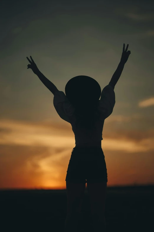 a woman that is standing in the grass with her arms up