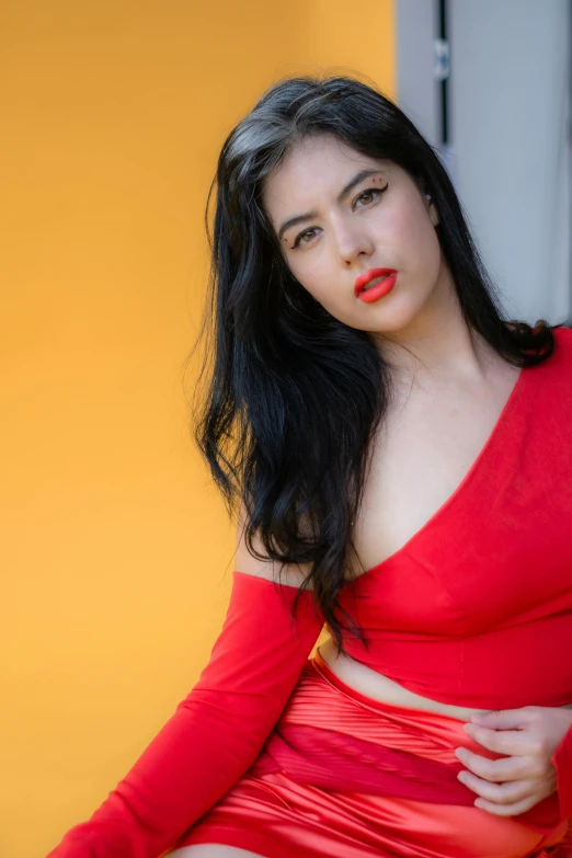 woman with red lipstick posing in front of yellow wall