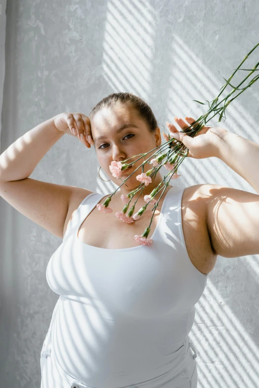 a woman holding up three flowers to her head