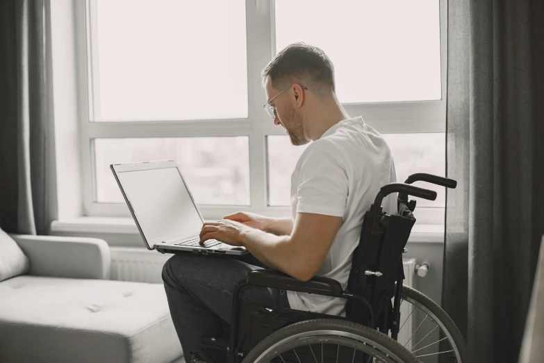 a man in a wheel chair using his laptop