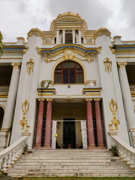 the entry to an old style building with ornate red and gold columns