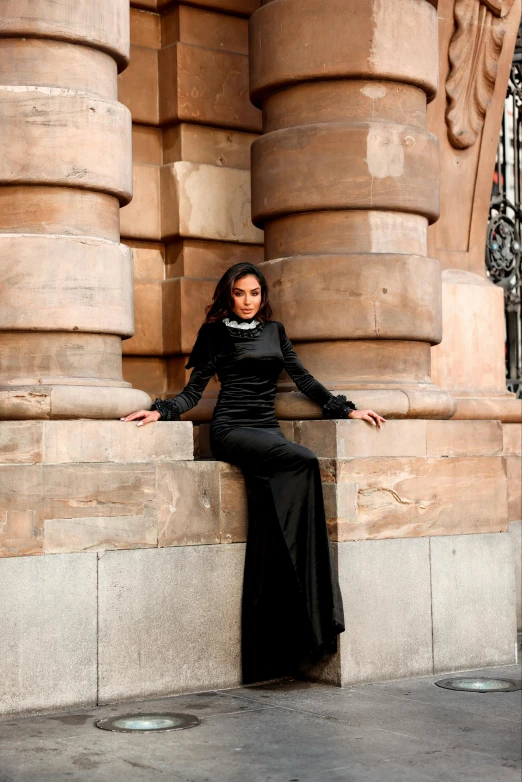 the woman is sitting against a stone wall