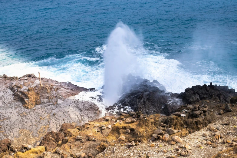 a large wave crashing on rocks at the ocean