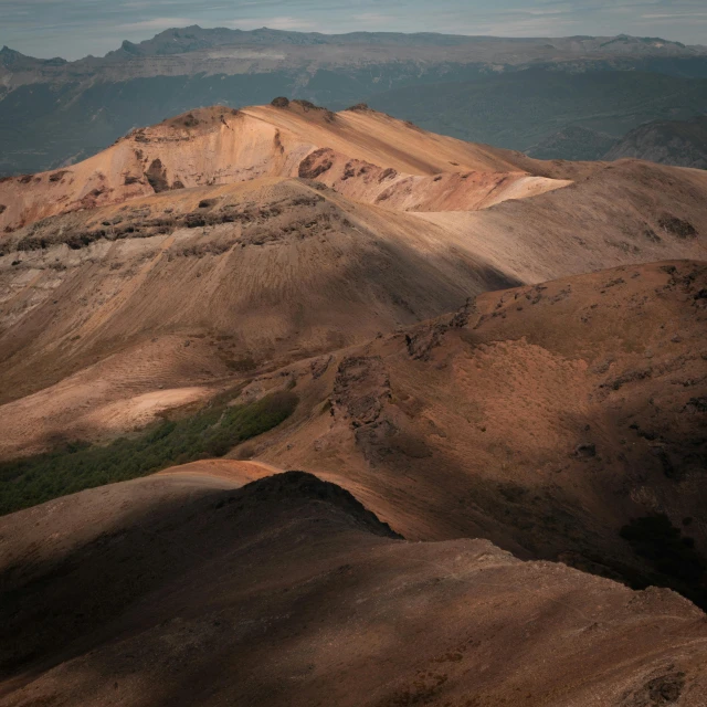 a view from an airplane of mountains with small patches of dirt on the ground